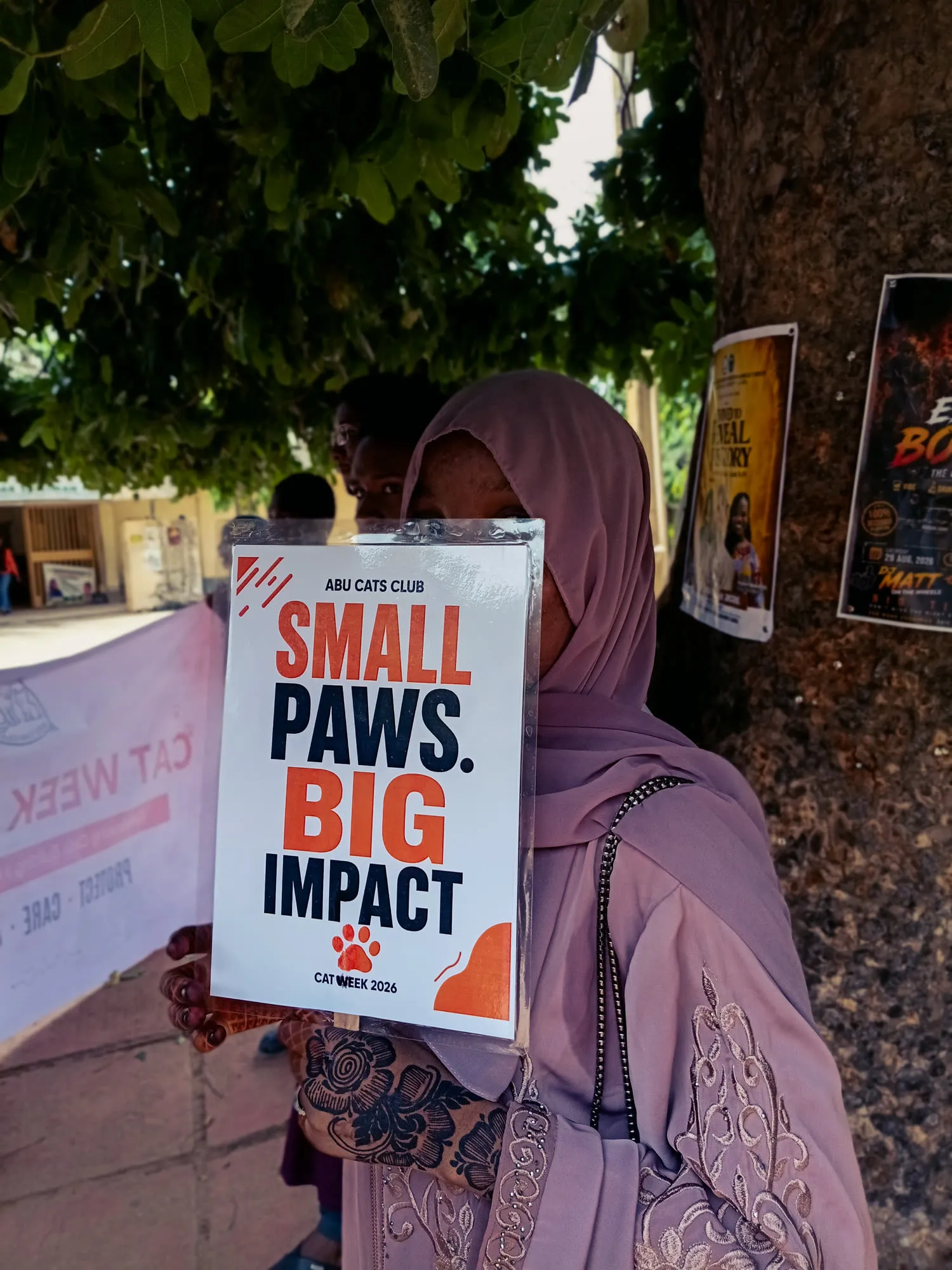 A student holding a placard reading Small Paws, Big Impact
